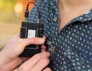 Lapel mic with battery pack being clipped onto a shirt