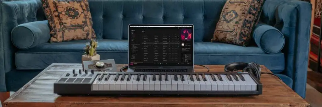 MIDI keyboard, audio interface, headphones, and laptop for music production.