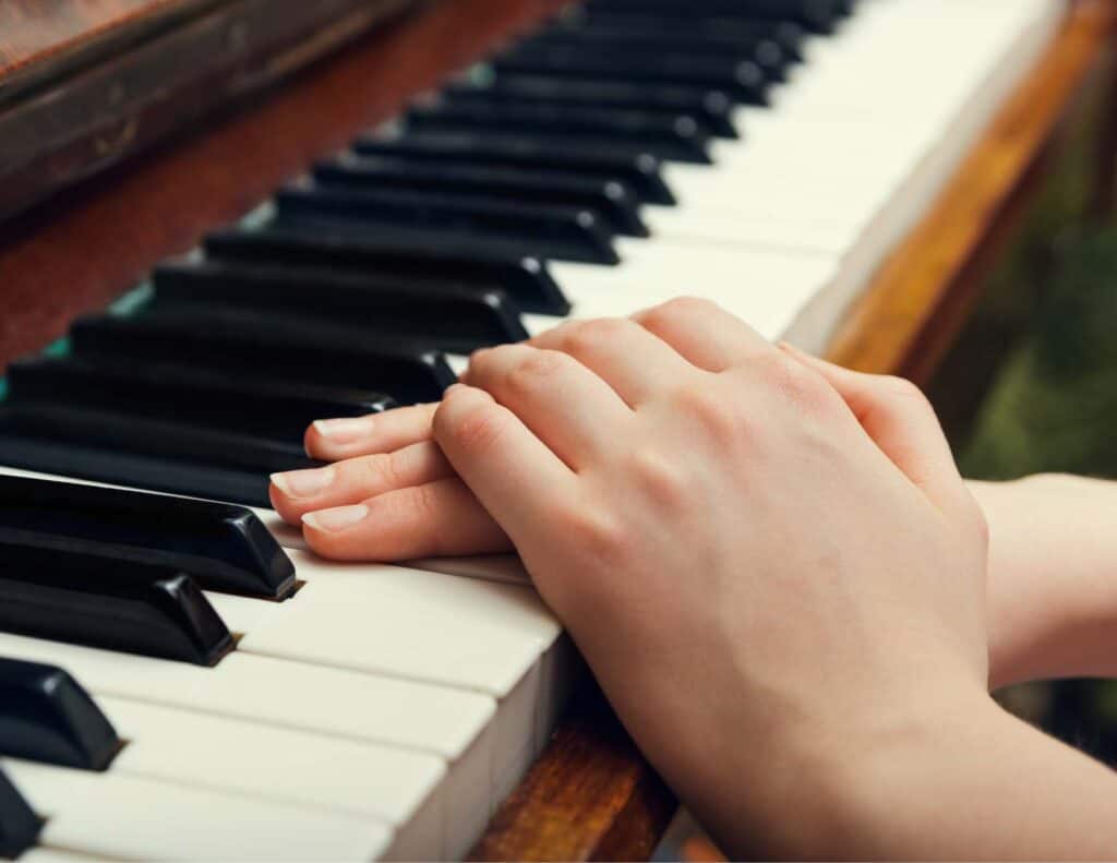 Hands resting on a piano keyboard.