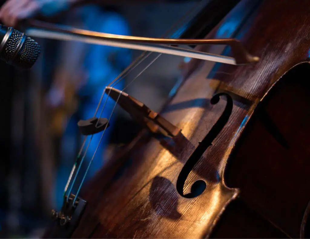 A microphone positioned close to the 'F' holes of a cello.